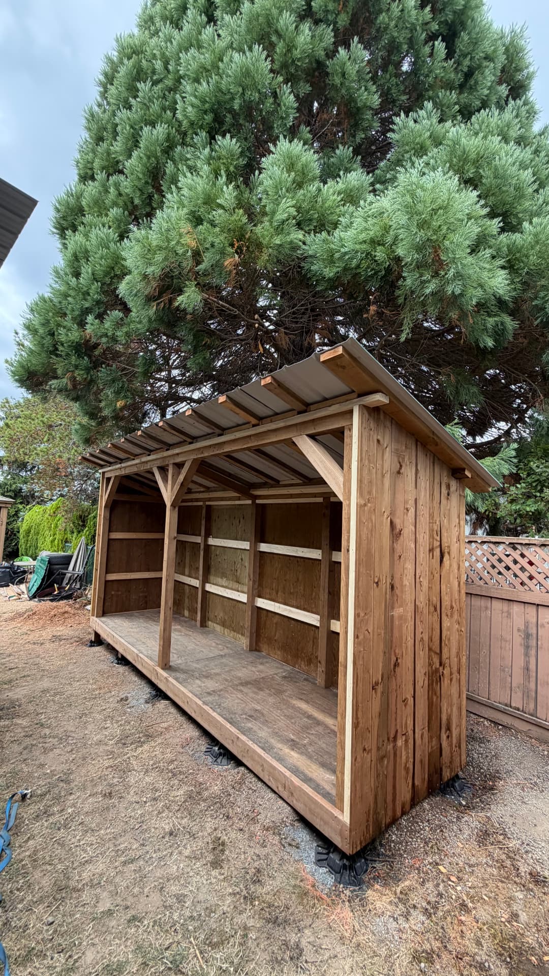 Open-front cedar storage structure with a corrugated roof built by Bellstone Property Services
