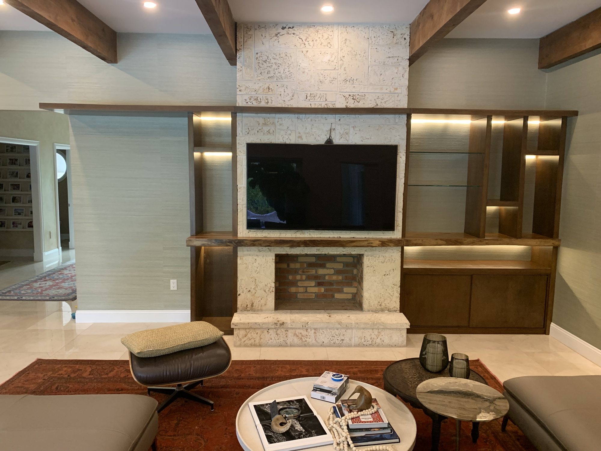 Custom dark wood shelving and cabinetry installed around a stone fireplace and television