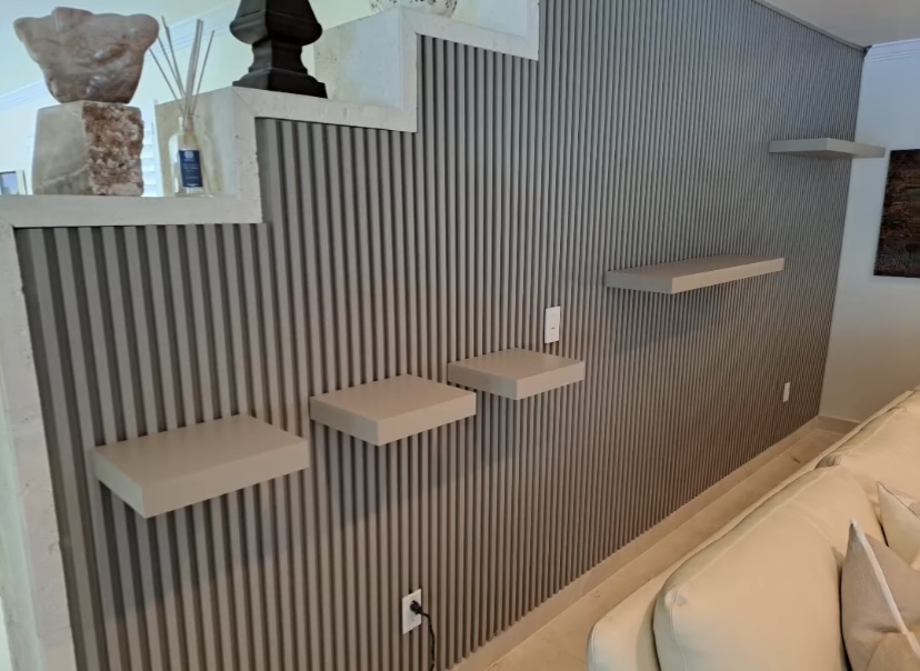 Grey vertical slat feature wall with custom floating display shelves beside a staircase